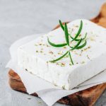 Homemade greek cheese feta with rosemary and herbs on wooden board