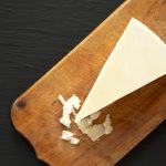 Pecorino Romano Cheese on a rustic wooden board on a black background, top view.